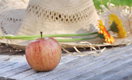 apple placed before a straw hat in a garden in summerの写真素材
