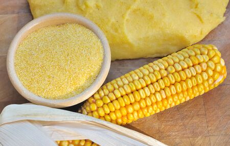 ear of corn between flour and polenta on wooden board