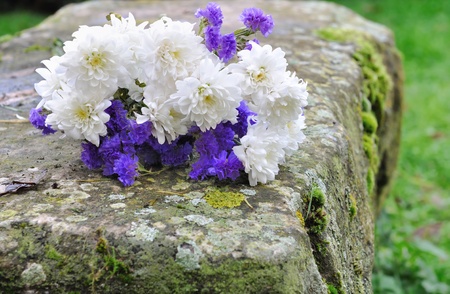 bouquet of white flowers and purple sitting on a stone benchの写真素材