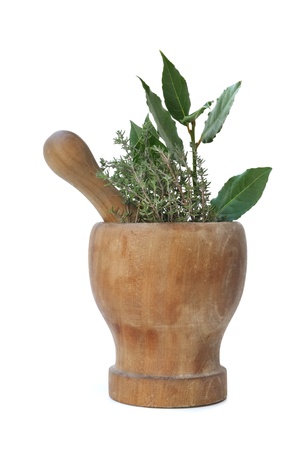 branches of bay leaves and thyme in a wooden pestle on white backgroundの写真素材