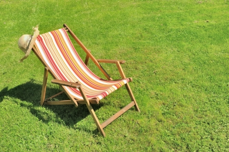 lounge chair and straw hat on sunny lawnの写真素材
