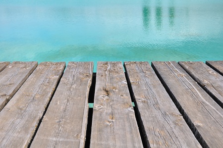wooden terrace at the edge of the turquoise water of a swimming poolの写真素材