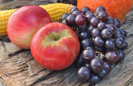 bunch of black grapes with red apples on  wooden backgroundの写真素材
