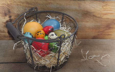 colorful easter eggs in a basket on wooden backgroundの写真素材