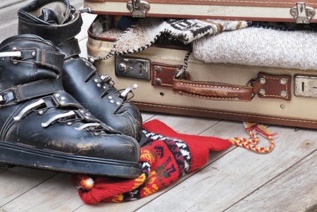 small open suitcase full of warm clothes with old ski bootsの写真素材