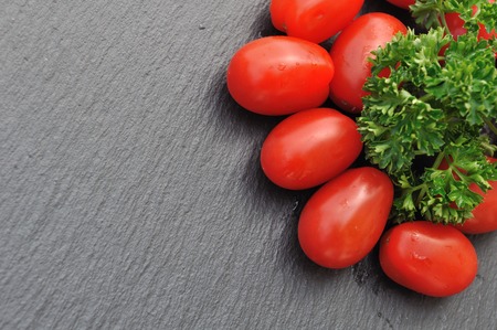cherry tomatoes with parsley on slate backgroundの写真素材