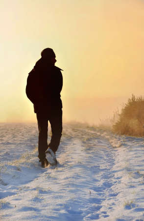 man silhouette walking on a rural path in winter on sunsetの写真素材