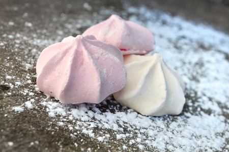 strawberry and vanilla meringues on sugar on wooden plank