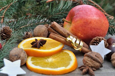 orange, apple, walnuts and spices on wooden background with Christmas decorationの写真素材