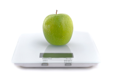 green apple on a scale isolated on white backgroundの写真素材