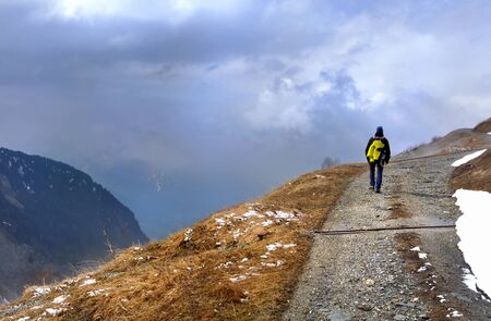hiker on a mountain path by bad weather