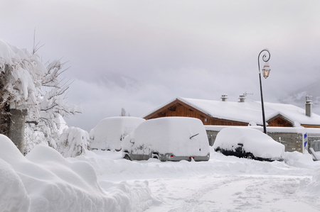 cars covered by snow parking in a village の写真素材