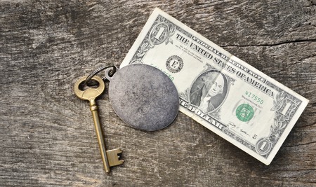 old key in a ring with money on old wooden plank の写真素材