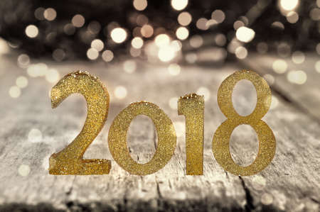 golden figures 2018 on a wooden plank in front lightsの写真素材