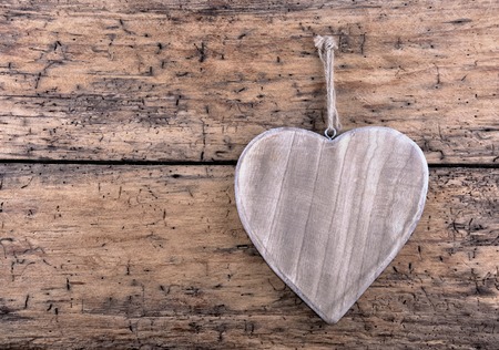 big wooden heart hanging on a rustic plank の写真素材