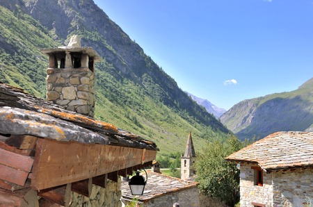 roof of house of a old village with chimney  and bell tower of church in mountainの写真素材