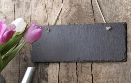 slate hung by sting at a rustic plank with tulips on the sideの写真素材