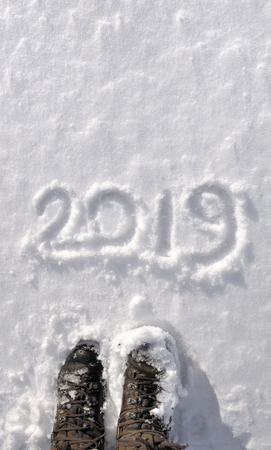top view on 2019 written in the snow and hiker feetの写真素材