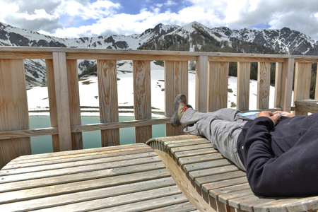 man relaxing in terrace with view on a mountain lakeの写真素材