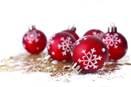 red christmas baubles with snowflakes shape on golden glitters isolated on white backgroundの写真素材