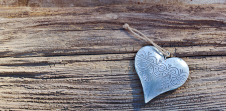 decorative metal heart  on a rustic wooden backgroundの写真素材