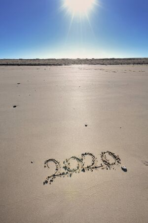 2020 written on the sand under a beautiful sunny blue sky