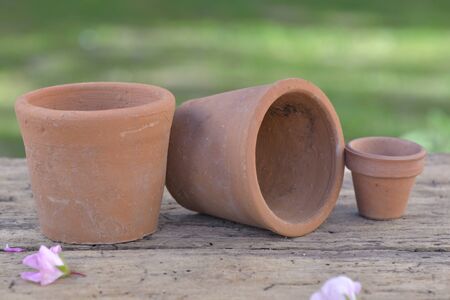 group of terracotta flowerpots put on wooden table in a garden