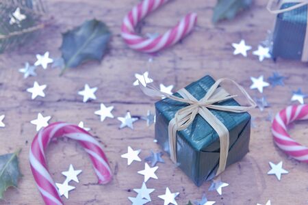 close on a gift in christmas decoration with   candy canes and  star shaped confetti on rustic