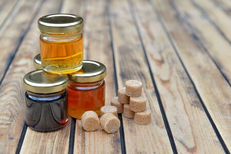 little glass pots of various honey and brown sugar on a wooden table