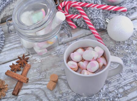 mug full of marshmallows on a milk chocolate with spices and christmas decorationの写真素材
