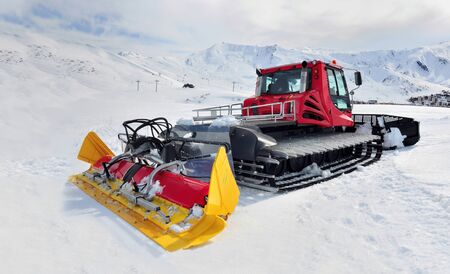 groomer red and yellow parking on ski slope in alpine resort