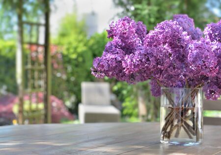 beautiful bouquet of purple lilac flowers on a wooden table in garden の写真素材