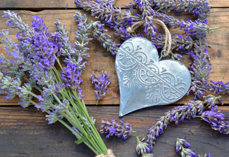 decorative metal heart among flowers of lavender on wooden backgroundの写真素材