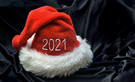 2021 on red santa claus hat in black textile backgroundの写真素材