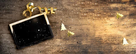 little board on rustic wooden background with golden confetti and ribbon