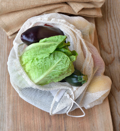 fresh vegetables in a reusable bag put on a wooden tableの写真素材