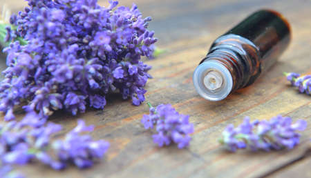 bottle of essential oil and bouquet of lavender flower on a wooden tableの写真素材
