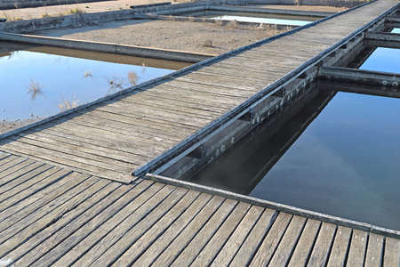 wooden walways crossing old seawater ponds for oyster farming