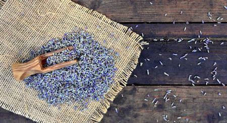wooden spoon in petals of lavender flowers put on textile and wooden backgroundの写真素材