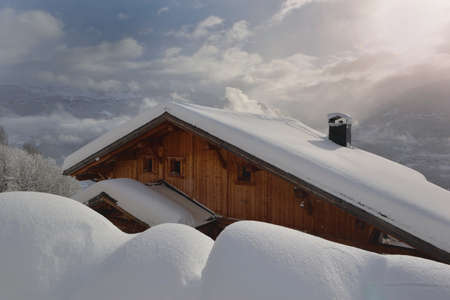 wooden chalet in alpine village covered with fresh snow in mountain landscapeの写真素材