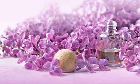 bottle of essential oil in front of purple lilac flower backgroundの写真素材