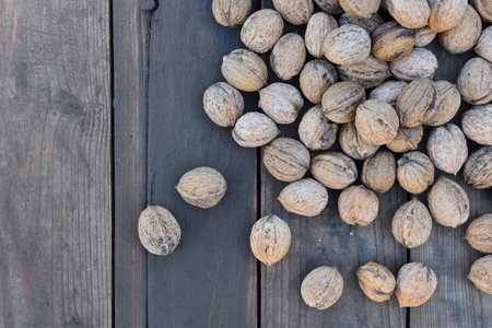 top view on walnuts in their shell spread on a plank