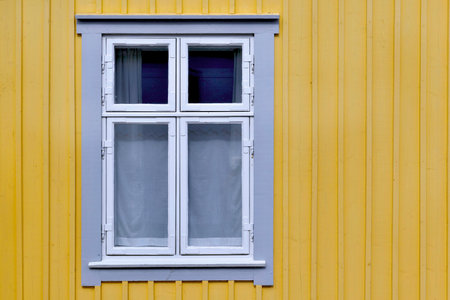 closeup on window on a facade of a sweden house painted in yellowの写真素材