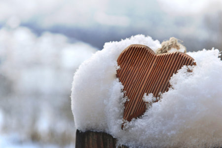 closeup on wooden decorative heart put in the snow outdoorsの写真素材