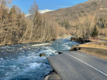biking road at the edge of a river flowing in an alpine valley destroyed during a flood in Savoyの写真素材