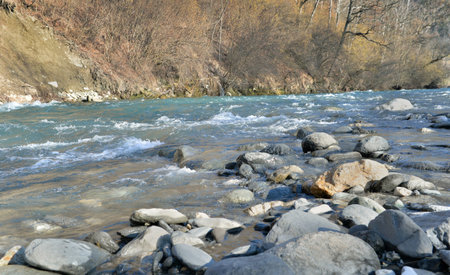 stones in a beautiful alpine river flowing in forest bank in springの写真素材