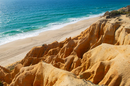 beautiful beach in the Atlantic Ocean bordered by yellow hard sand cliffs forming a canyon Medides beach in Portugalの写真素材