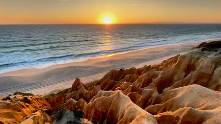 beautiful sunset on a beach in the Atlantic Ocean bordered by hard sand cliffs forming a canyon Medides beach in Portugalの写真素材