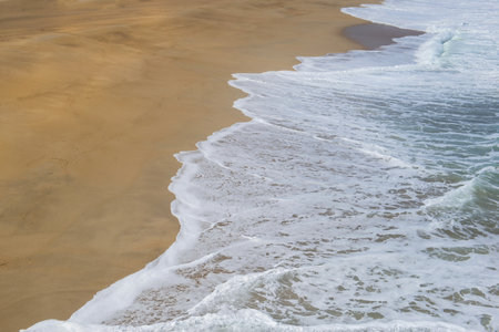 view high on the waves depositing foam on a beach on the west coast of Portugalの写真素材