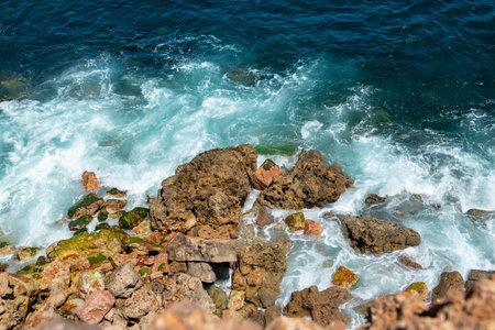 view from the top of the sea with waves hitting the rocks forming foam in the portugal coast in...